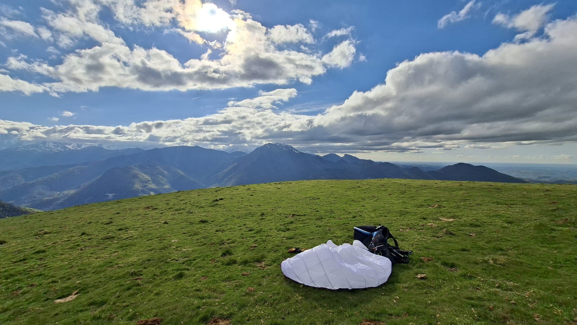 Voile blanche posée au décollage après un vol, panorama de la vallée d'Aure en arrière-plan.